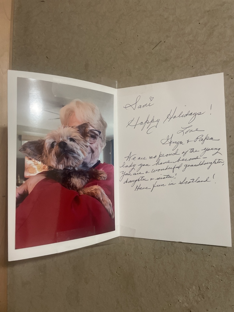 Handwritten card with holiday wishes with a photograph of an elderly person holding a small brown and black fluffy dog (named Ginga).